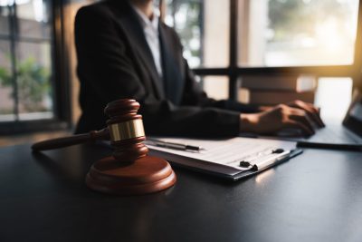 Working at desk by gavel – shutterstock_2213729987
